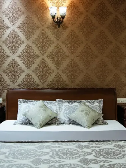 A close-up of the bed and side tables, highlighting the detailed woodwork and the classic lamp that adds to the room's warm ambiance.