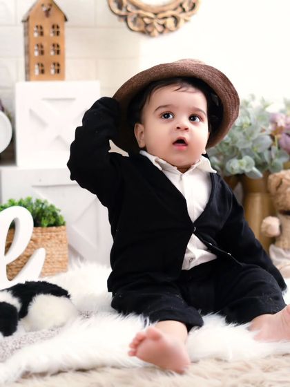 A handsome little gentleman celebrating his first birthday. His sweet expression and smart outfit make for a timeless and classic portrait.