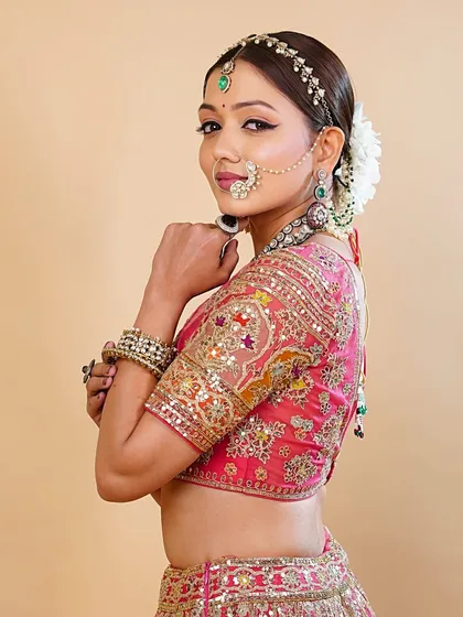 This side portrait shows how the makeup and hair come together to create a clean, regal silhouette, perfectly complementing the vibrant bridal lehenga.