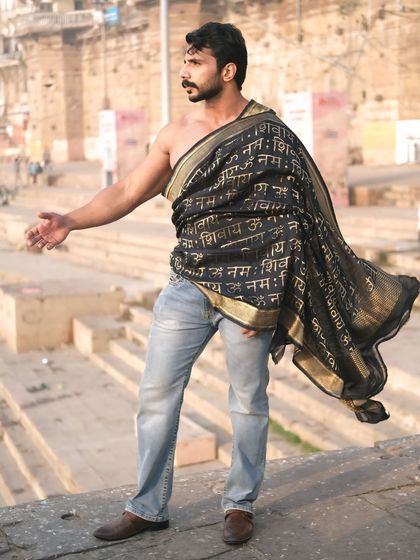 A dramatic pose with an outstretched arm, echoing the expansive ghats and the flowing river, capturing a moment of powerful expression.