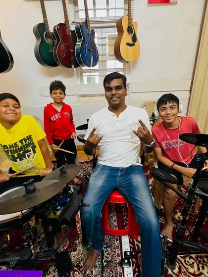 Our drum coach and his students are all smiles and rock signs. The camaraderie and fun in our drum classes are just as important as learning the beats.
