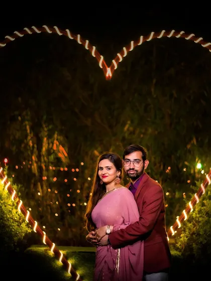 A classic romantic portrait framed by a large, illuminated heart. This is a popular and beautiful setup for nighttime pre-wedding photography.