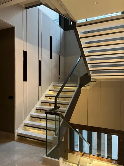 The interplay of vertical and horizontal lines on the wall and stairs creates a bold, cohesive statement, demonstrating our philosophy of integrated architectural design.