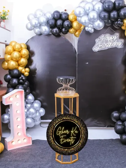 A Tom & Jerry themed first birthday with a sleek black, gold, and silver color scheme. The setup includes character cutouts, a large marquee number '1', and a stylish balloon arch.