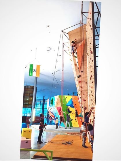 A young climber confidently makes her way up our tall climbing wall, secured by a top-rope. This is a great example of the focus and achievement we see in our kids climbing programs every single day.