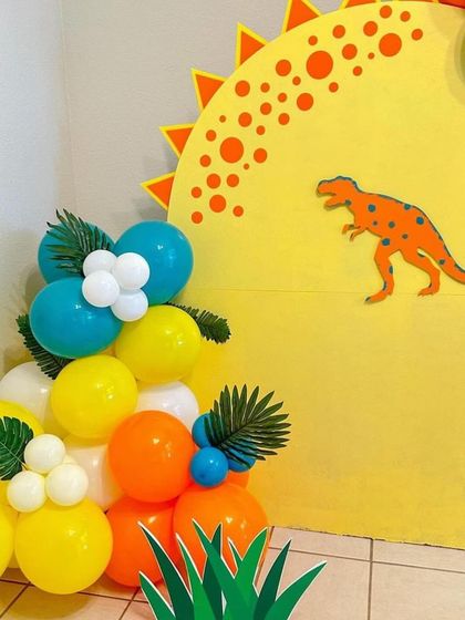 A close-up of our colorful dinosaur party decor, showing the balloon details and the fun, bright yellow backdrop.