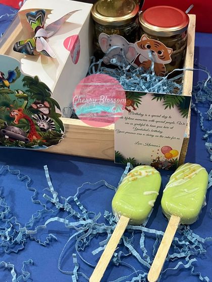 Our jungle-themed return favours are filled with delicious treats baked fresh in our own bakery. This pinewood tray includes jars of goodies, cakesicles, and a pop-up butterfly card.
