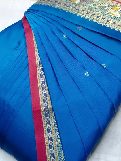 A beautiful blue Paithani-style saree. The pleats are set to showcase the intricate border design, making it a true statement piece.