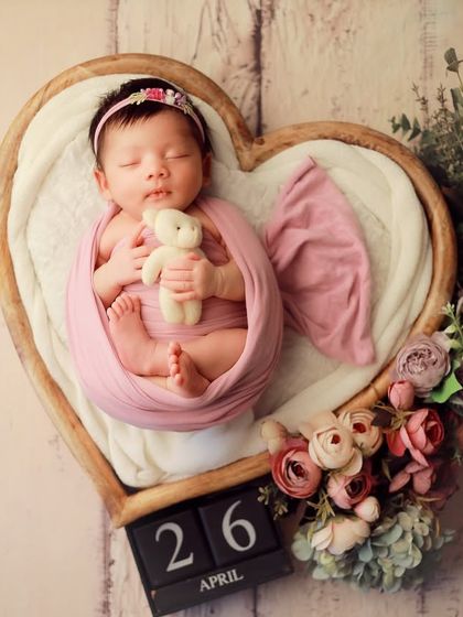 This sweet baby girl is nestled in a heart-shaped prop, surrounded by delicate flowers. We use a date block to mark the special day, creating a beautiful birth announcement photo.