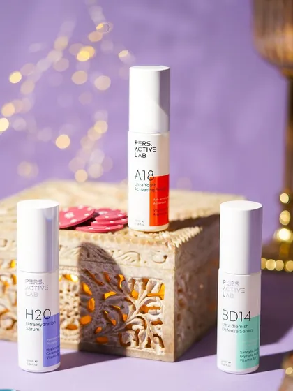 A festive arrangement of skincare products on an ornate wooden box with poker chips. The bokeh lights in the background add a magical sparkle, blending beauty with Diwali celebrations.