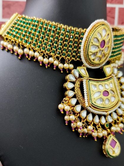 A close-up of the necklace, showing the vibrant green beaded choker and the large kundan pendant.