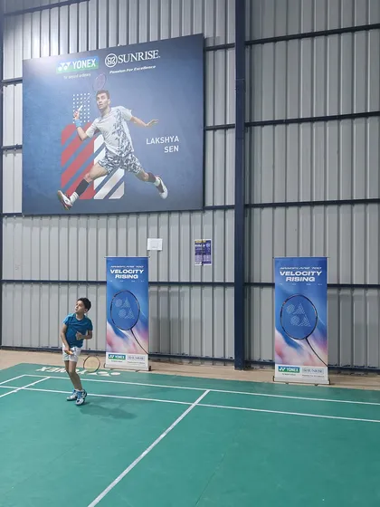 A player takes a shot on the court during our special event with Yonex. The atmosphere is always energetic and motivational, surrounded by banners of badminton champions.