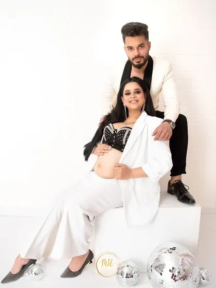 A chic and modern couple's portrait. The couple poses in stylish black and white outfits, surrounded by disco ball props for a fun, contemporary vibe.