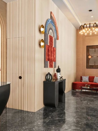A wider view of the banquet hall's lounge area, where a plush red sofa adds a bold pop of color. The combination of modern art, geometric patterns, and warm lighting creates an inviting space for guests to relax.