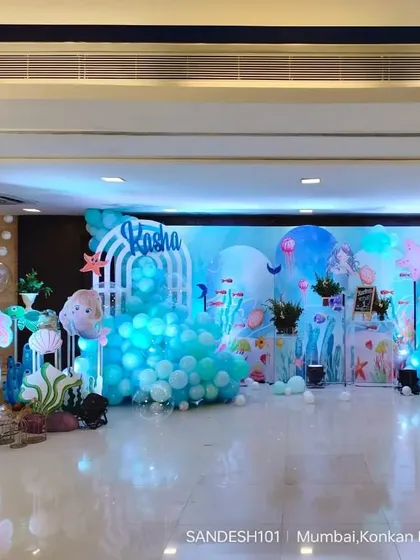A wide view of the entire mermaid themed stage decoration. The hall is transformed into an underwater kingdom with blue lighting, balloon bubbles, and sea-themed props.