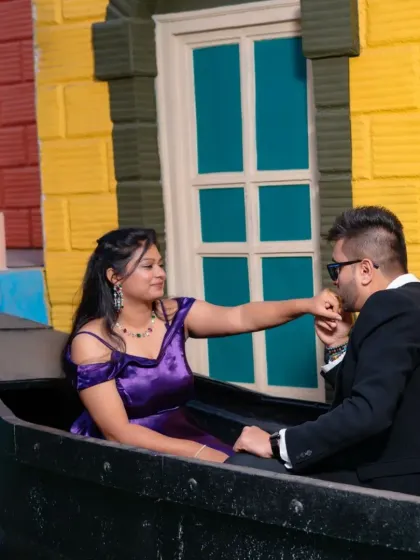 A playful and romantic moment. The groom's chivalrous gesture is the perfect complement to the bride's beautiful off-shoulder purple gown.