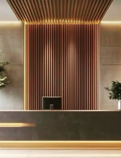 A striking reception area with a minimalist dark stone desk, accented by warm lighting from below. The back wall features dramatic copper-toned fluted panels, creating a luxurious and memorable first impression.