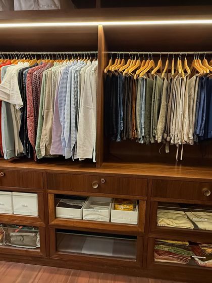 This section of a walk-in closet is dedicated to men's shirts and trousers, organized by type and color for a clean, streamlined look.