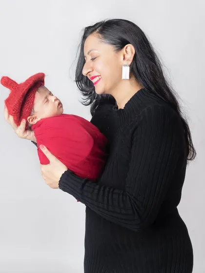 A beautiful smile from a mother as she holds her sleeping newborn. A portrait of pure contentment.