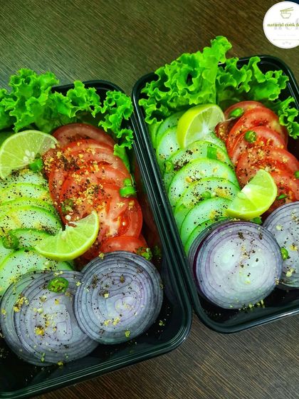 A simple, fresh salad of cucumber, tomato, and onion, seasoned and ready to be packed.