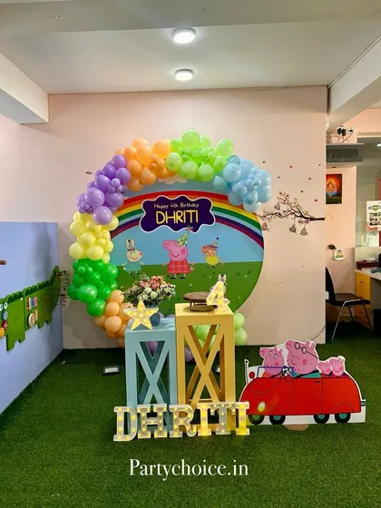 A cheerful Peppa Pig theme for a 4th birthday. This setup includes a rainbow balloon arch, a custom backdrop with Peppa's family, and a cutout of their iconic red car.