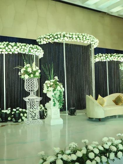 A minimalist stage design featuring clean black panels topped with clouds of white flowers. This creates a dramatic and sophisticated contrast, perfect for a modern reception or cocktail event.