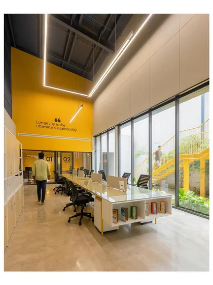 This open-plan workspace for Prime Ply's office in Kannur was designed to foster collaboration and creativity. The high ceilings, abundant natural light from floor-to-ceiling windows, and vibrant color accents create an energizing atmosphere.