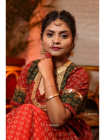 A close-up shot focusing on the details of a traditional look. The model's pose with her hand near her face highlights the nose ring, ring, and intricate patterns of the blouse.