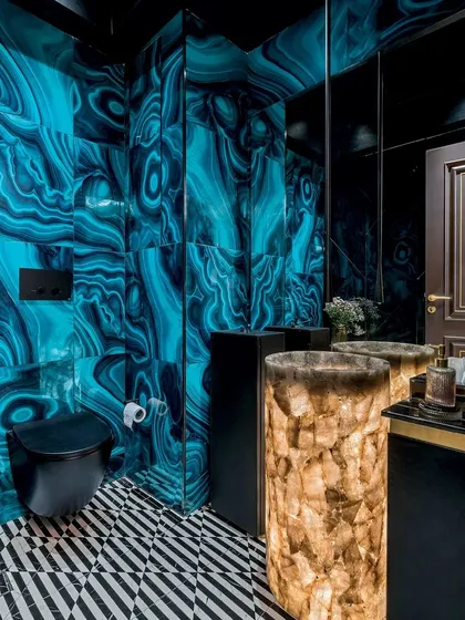 A stunning powder room with bold, malachite-patterned walls and a backlit stone pedestal sink, featured in Architecture + Design to showcase our daring use of color and material.