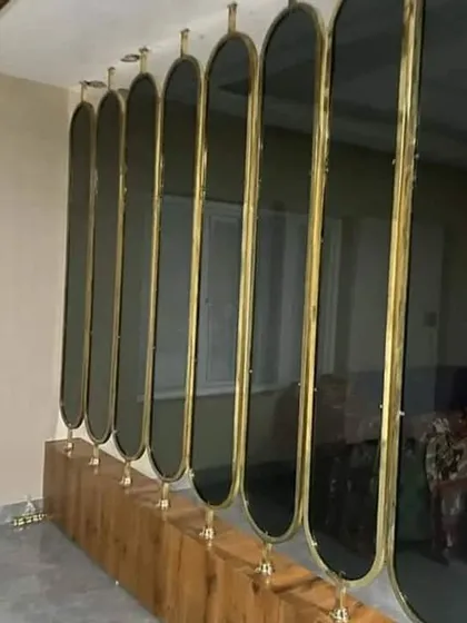 A stylish partition design using vertical oval panels of tinted glass with a brass-finished frame. This element elegantly divides a space without blocking light, adding a touch of art deco sophistication.