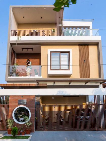 The completed Sarjapur Road residence, built on a compact 1500 sq. ft. plot. The facade is simple and elegant, with accent brick cladding, vertical MS louvers, and a warm color tone.