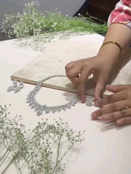 A stylist's hands at work. This behind-the-scenes shot shows the careful placement of a fine jewellery set for a flatlay, ensuring every piece is perfectly positioned.