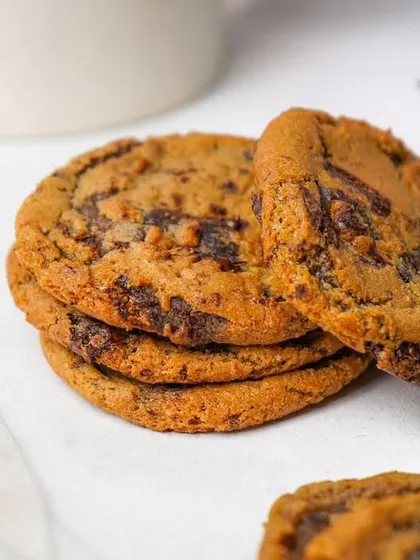 A tempting pile of chocolate chip cookies, with one leaning against the stack. The clean, simple styling keeps all the attention on the delicious product.