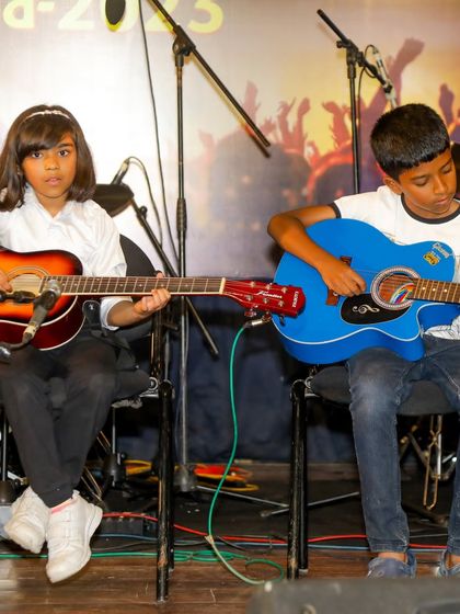 Two young guitarists performing together, a testament to the social skills and teamwork developed through our music programs.