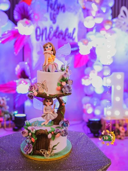 The full two-tiered enchanted forest cake, featuring a fairy on a swing and another sitting on top. This was the centerpiece of the dessert table.