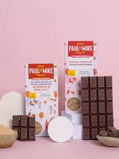 A minimalist and modern product shot of two chocolate bars on geometric blocks. The clean lines and simple composition give it a very sophisticated and high-end feel.