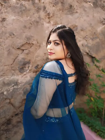 A lovely over-the-shoulder pose showcasing the back of her hairstyle and the sheer sleeves of her blouse.