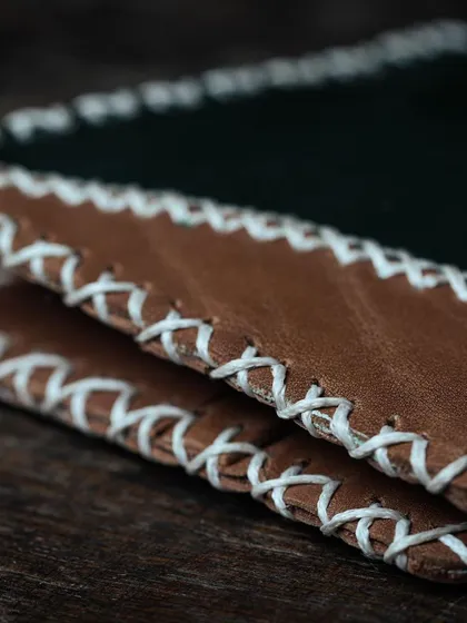A detail shot of the cross-stitching on a handmade leather wallet. Our workshops cover fundamental techniques, including stitching, finishing, and construction.