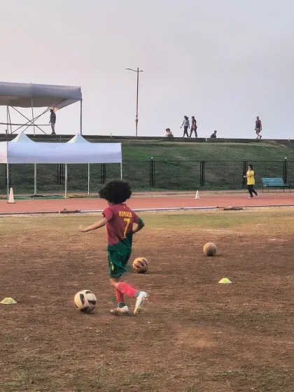 A young player with great focus practices his dribbling skills around cones. This fundamental drill is key to developing the ball control needed to become a confident footballer.
