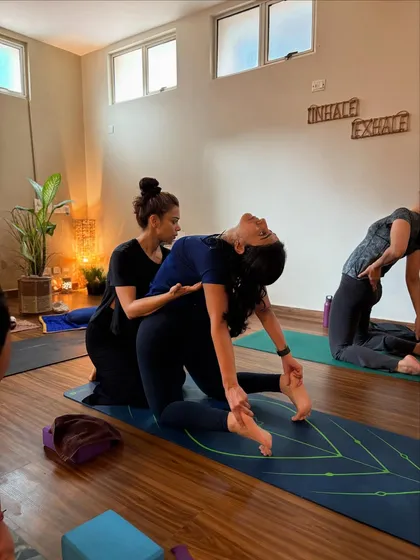 Guiding a student deeper into Ustrasana (Camel Pose). My hands provide support for her lower back, allowing her to open her chest and throat with confidence.