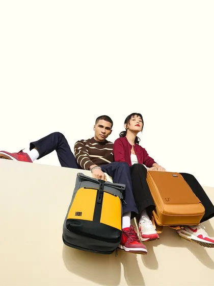 A high-fashion shot for an accessories campaign. The makeup is clean and sharp, with a focus on defined features that complement the models' strong poses and the modern aesthetic of the brand.