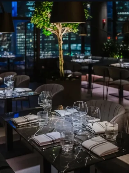 A beautifully set table at One40 Rooftop, where a tree stands against the backdrop of city lights. This detail shows our commitment to bringing natural elements into every space we design.
