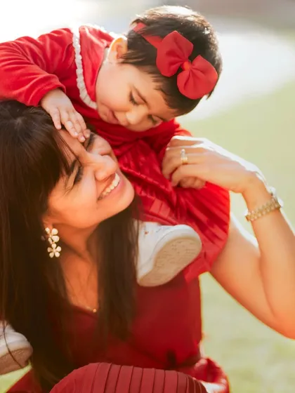 A mother and daughter enjoying a sunny day outdoors. The matching red outfits are a beautiful touch.