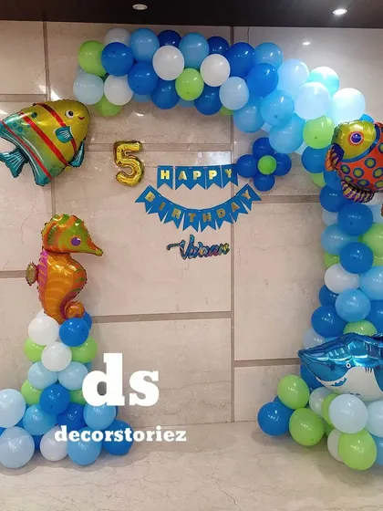 An underwater adventure with this ocean-themed balloon decoration. The blue, green, and white balloon arch is decorated with foil balloons shaped like a shark, seahorse, and tropical fish.