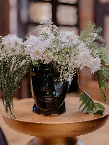 A unique floral arrangement in a black face-shaped vase, a quirky and artistic detail that perfectly matched the high-concept theme.
