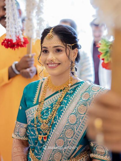 A beautiful look for another wedding function in a teal blue saree. The makeup is kept fresh and glowing, with traditional jewelry and the essential Mundavalya for the ceremony.