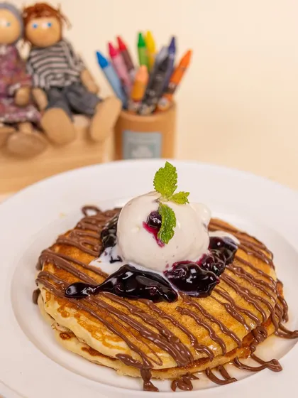 Pancakes aren't just for breakfast! Our fluffy pancakes topped with ice cream, chocolate, and blueberry compote are a decadent dessert or a special treat.