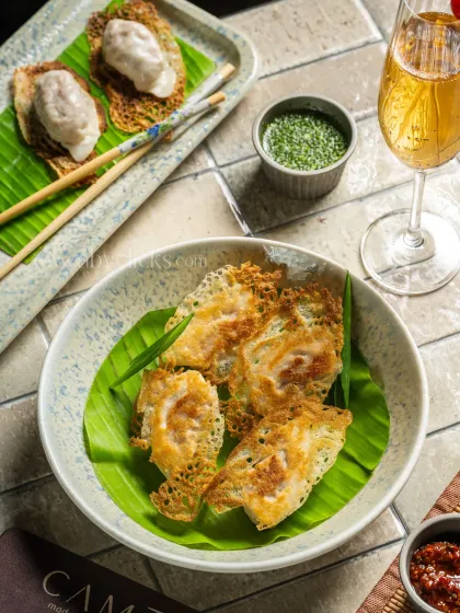 Crispy, pan-fried dim sum served with wine, creating an upscale dining image for Camo, Noida.