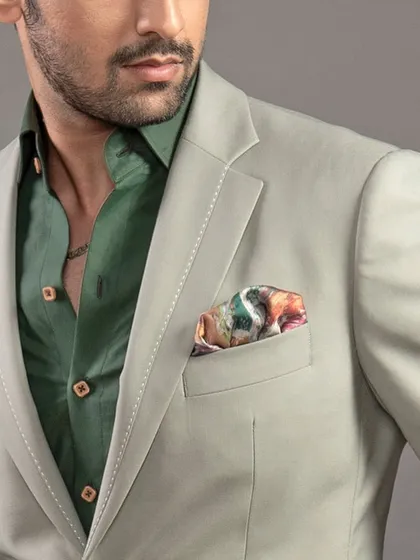 A close-up on the details of the sage green suit, showing the pick stitching on the lapel and the texture of the fabric. These details are a hallmark of quality craftsmanship.