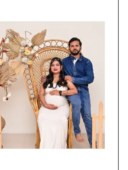 A relaxed couple's portrait in our Boho setting. The combination of a white dress and a denim jacket creates a casual yet stylish look, perfectly complemented by the natural textures of the wicker chair and decor.